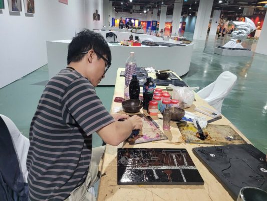 Hoạt động biểu diễn vẽ tranh sơn mài truyền thống tại Triển lãm thành tựu đất nước